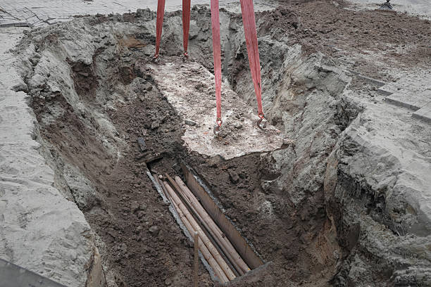 istock Large construction site excavation with exposed underground pipes and red hoisting straps 2236743683