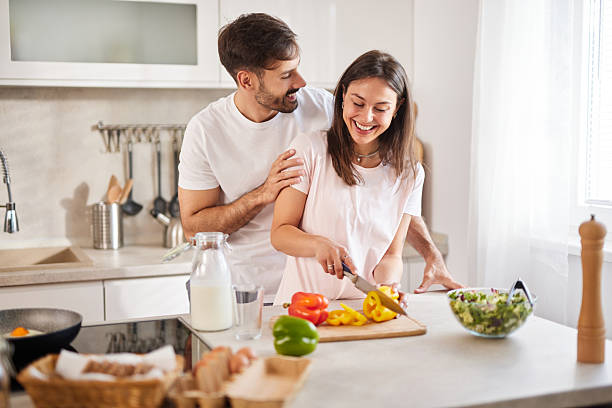 istock Happy couple preparing food and smiling in a modern kitchen 2236745565