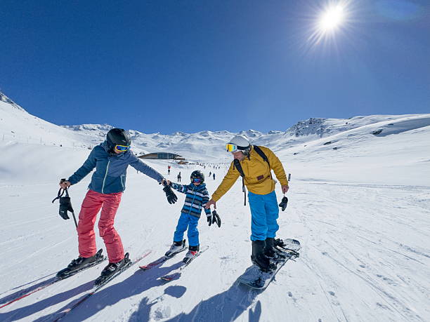 Family skis groomed ski run on sunny day, Val Thorens