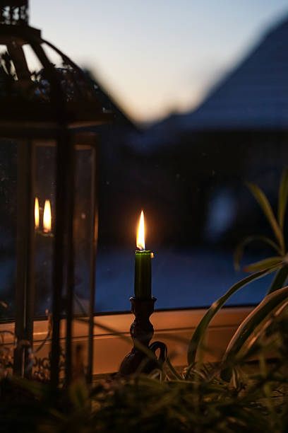 Candle light on the window sill, dark room, early winter morning