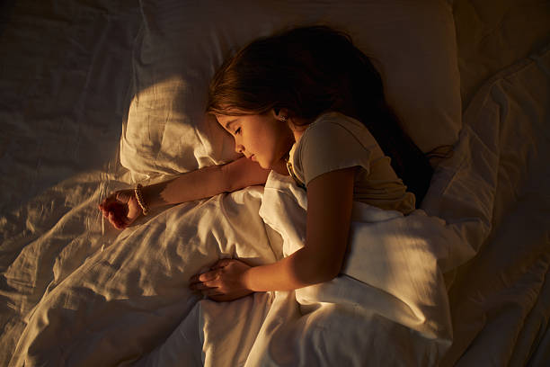 istock Young girl sleeping peacefully in bed with morning sunlight 2236746590
