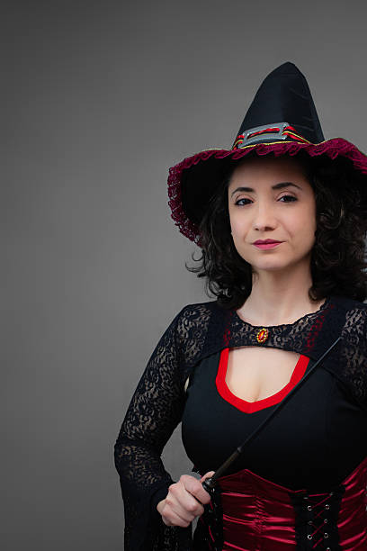 istock Charming mid-adult witch holding a magic wand, looking at camera. 2236747330