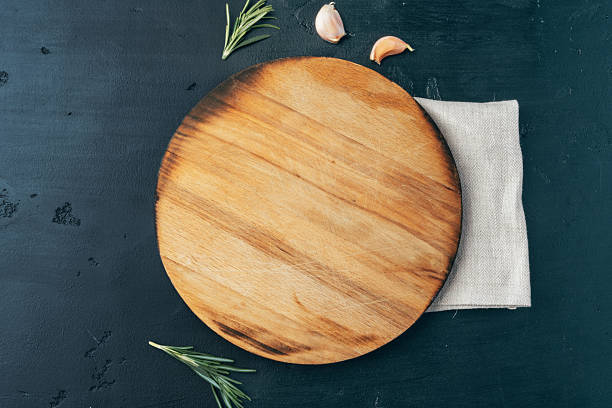 istock Empty wooden board with garlic and rosemary on black background 2236747910