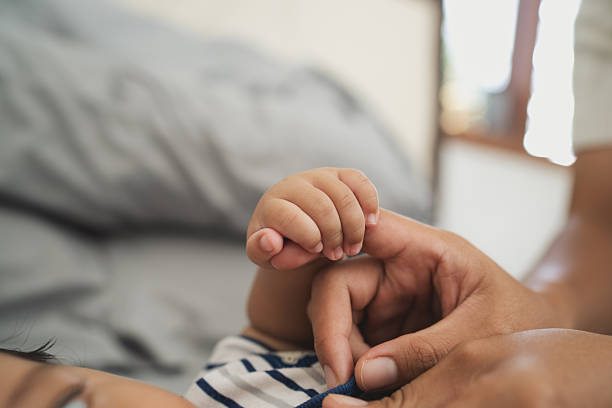 istock Close up baby finger holding mother hand 2236751614
