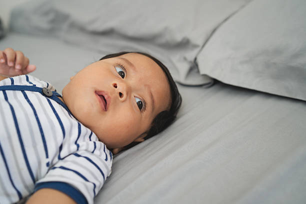 istock Baby resting calmly on bed indoors with striped outfit 2236751919