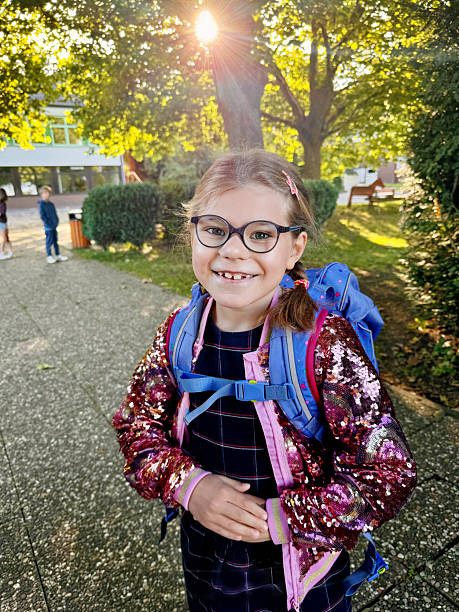 istock Happy little elementary school girl with eyeglasses and satchel backpack walking outdoors on the way to school. Smiling pupil child ready for back to school, education and childhood lifestyle concept. 2236752951