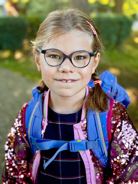 istock Happy little elementary school girl with eyeglasses and satchel backpack walking outdoors on the way to school. Smiling pupil child ready for back to school, education and childhood lifestyle concept. 2236752967