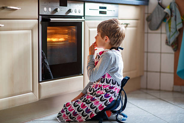 istock Cute blond boy baking muffins or pie in domestic kitchen. Happy child having fun with helping, sitting near ofen and waiting for cupcakes. Kid baking for Thanksgiving or Christmas holiday. 2236753405