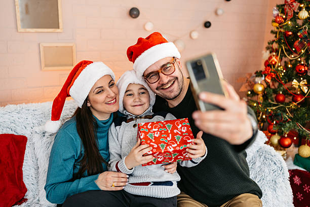 istock Mother And Father Taking Selfies Using Phone With Their Son On The Sofa At Home During Christmas Holidays 2236755014