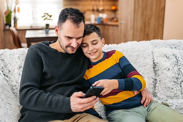 istock Father And Son Using A Phone Together On The Sofa At Home 2236755894