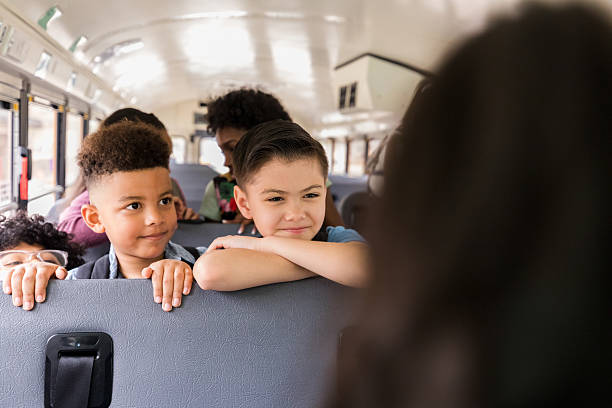 istock Happy elementary school children riding on a school bus 2236755933