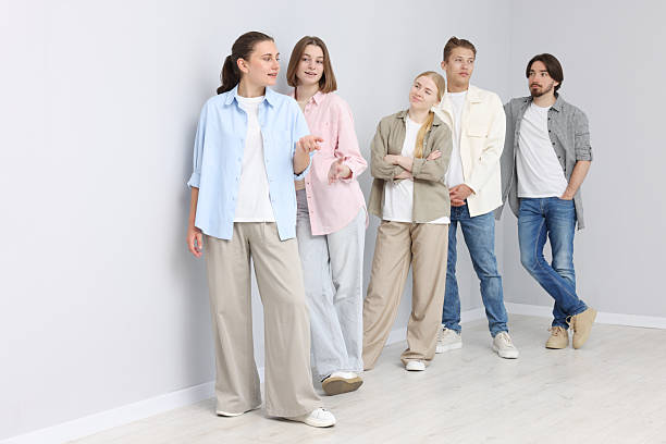 Group of people waiting in queue near light grey wall indoors