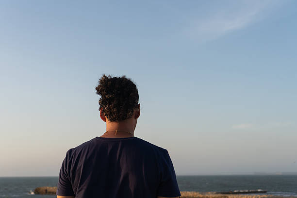 istock Man contemplating ocean view with curly man bun 2236757728
