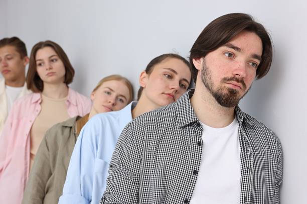 Group of people waiting in queue near light grey wall indoors