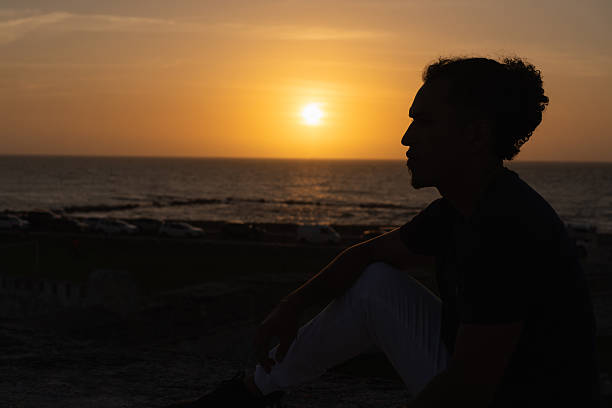 One man silhouetted against a golden sunset, contemplating the ocean view