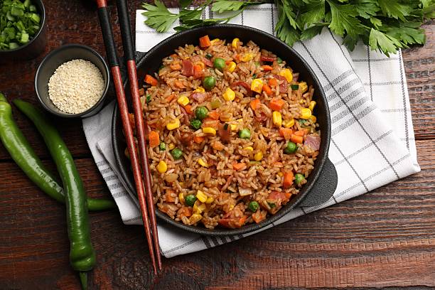 istock Delicious fried rice in baking dish served on wooden table, flat lay 2236759399