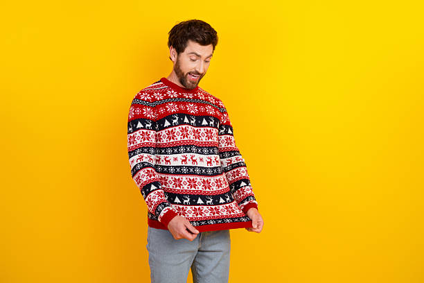 istock Man wearing festive sweater displaying joyful expression against vibrant yellow background 2236761640