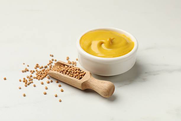istock Tasty mustard sauce and dry seeds on white marble table, closeup 2236761815