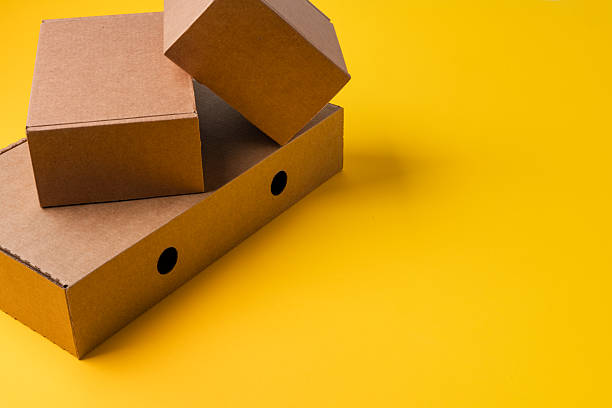 istock Beige cardboard boxes on yellow background, close up 2236763505