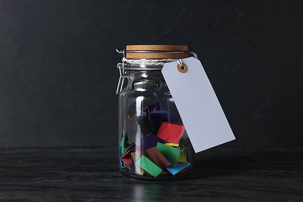 istock Colorful paper notes in glass jar with blank card on black table 2236763906