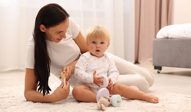 istock Smiling mother playing with her cute baby on floor at home 2236764549