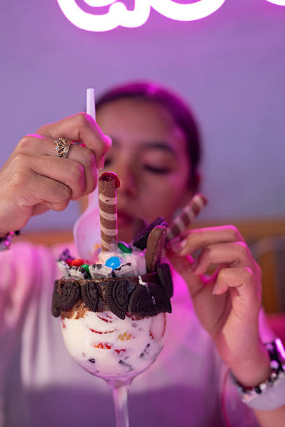 Woman enjoying dessert sundae with neon light