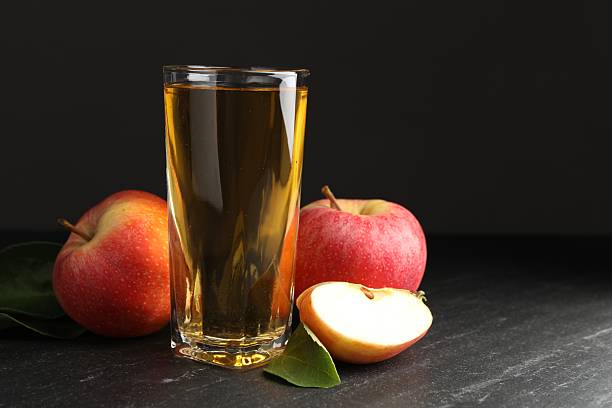 istock Fresh cider in glass, apples and green leaves on black table, space for text 2236765248