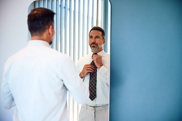 istock Confident mid adult man adjusting tie in mirror reflection 2236766328