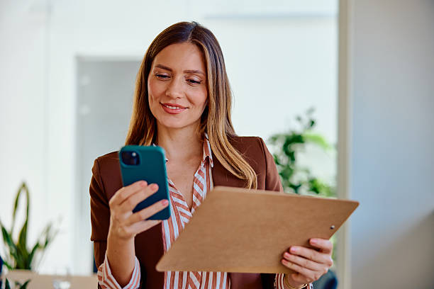istock Confident businesswoman using smartphone while holding clipboard 2236766751