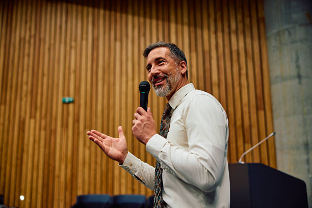 Confident mid adult man speaking at business conference presentation