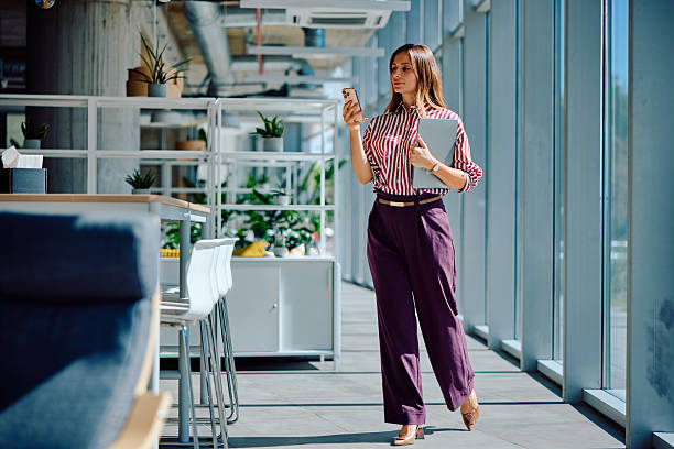 istock Confident young professional walking with smartphone in modern office corridor 2236767850