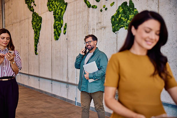 istock Diverse group of adults in modern office with green world map wall 2236767932