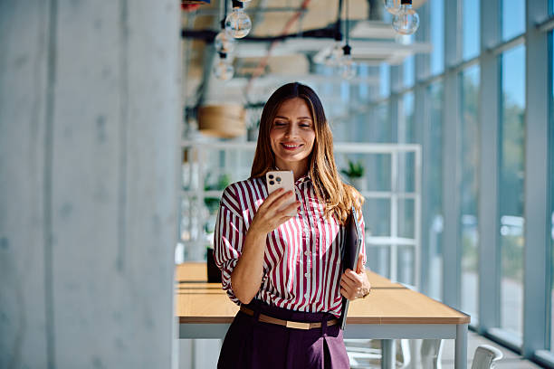 istock Smiling young businesswoman using smartphone indoors 2236768005