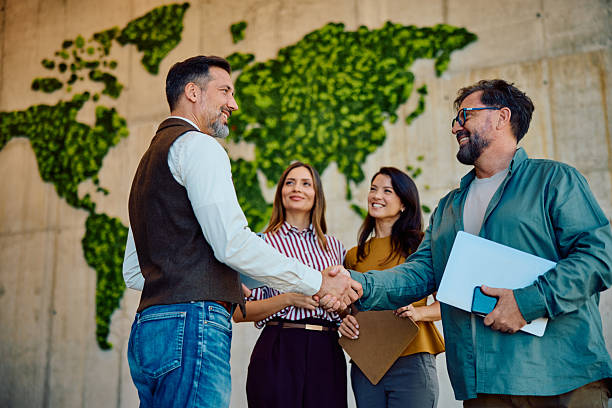 istock Successful business partnership handshake with world map background 2236768019