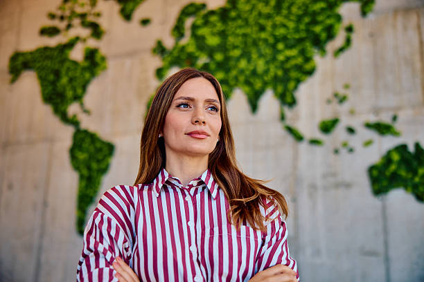 istock Confident young woman standing by green world map wall 2236768036