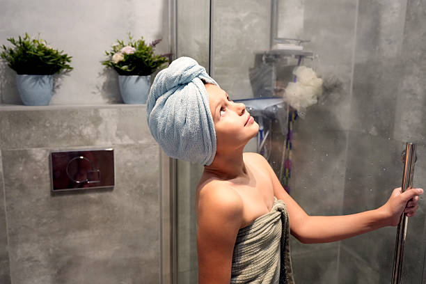 child with towel on body and head standing in modern bathroom after shower