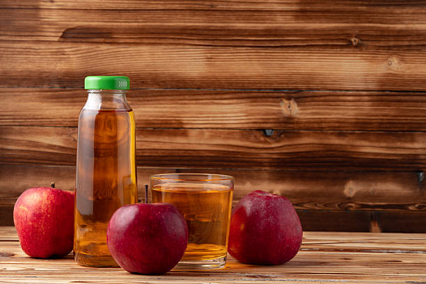 istock Apple juice in glass bottle with apples on table 2236769345