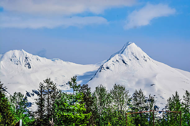 Snow-covered mountain peak in Alaska under a clear blue sky. Majestic winter landscape with pristine snow, rugged terrain, and untouched natural beauty. Ideal for concepts of wilderness, solitude, exploration, and cold climate.