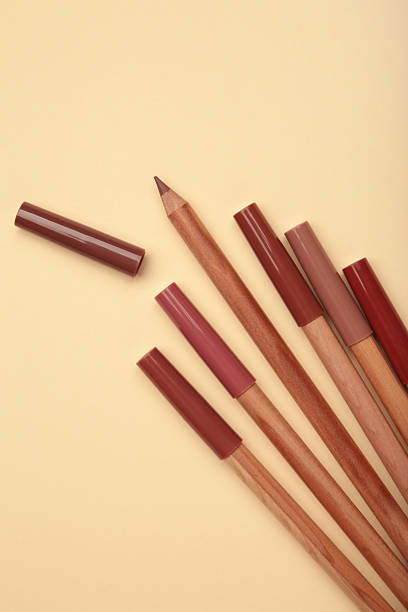 Different lip pencils on beige background. Cosmetic product. top view