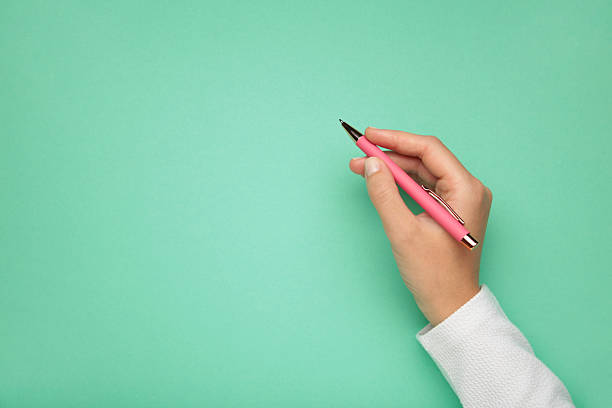 istock Young woman holding pink pen on mint background. 2236771504