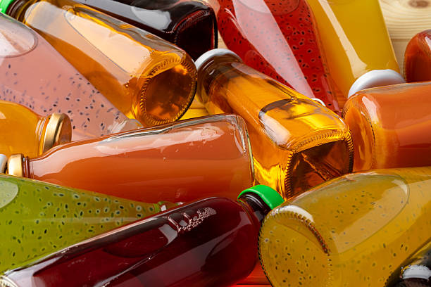Different bottles of juice on wooden table, close up