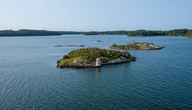 istock Small rocky island with lighthouse in calm sea.. 2236773607