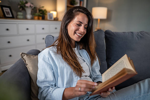 istock Relaxed young woman enjoying reading a book indoors 2236780798