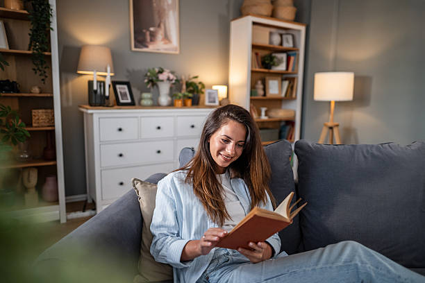 istock Young woman relaxing at home reading a book 2236780826
