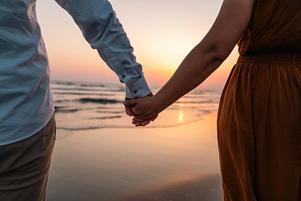 istock Couple holding hands at beach during sunset 2236786980