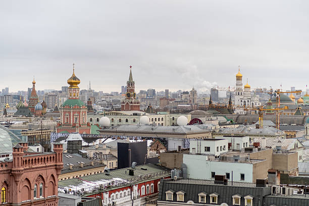 Diverse rooftops of Moscow include iconic domes and spires, blending history with urban life under an overcast sky during spring season.