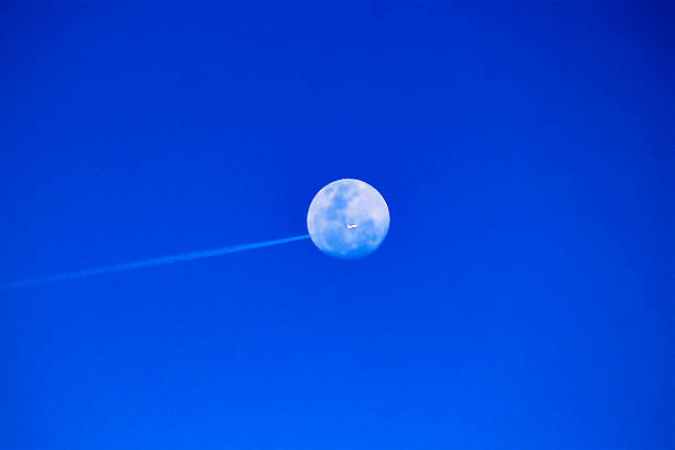 istock Moon, plane, and contrail against a brilliant blue sky 2236793832