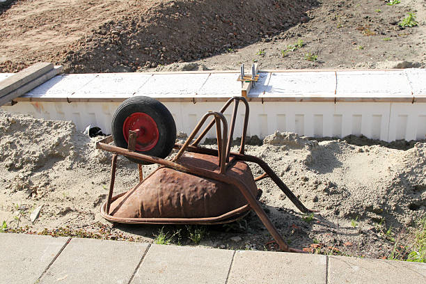 a wheelbarrow lies upside down at a construction with a ring beam for the foundation of a shed in the countryside