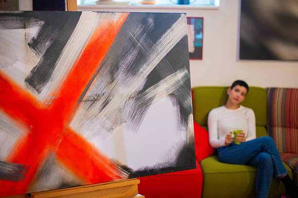 Beautiful young woman painter painting abstract painting at home.