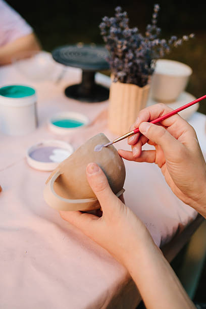 istock Artisan paints a ceramic cup with soft blue paint, capturing the detailed process of pottery decoration and handcrafted ceramic design. Girl is painting ceramic cup with blue paint at a table. 2236805237